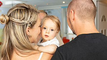 Eltern geben ihr Baby bei der Babybetreuung im Familienhotel Kaiserhof an der Zugspitze ab.